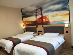 3 camas en una habitación de hotel con un cuadro en la pared en Thank Inn Chain Hotel Xinxiang Yuanyang Jianshe Road Hualong Shangjun, en Xinxiang