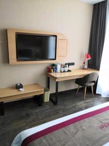 a room with a desk and a tv on the wall at Thank Inn Plus Hotel Guizhou Qiannan Duyun Wanda Plaza Store 