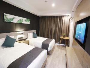 um quarto de hotel com duas camas e uma televisão de ecrã plano em Up and In Kashgar Xiyu Avenue Food Street em Kashgar