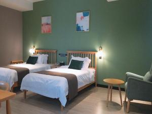 Cette chambre comprend 2 lits et un mur vert. dans l'établissement JUN Hotels Anhui Maanshan Hanshan Bus Station, à Jiulian