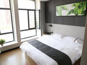 a bedroom with a large white bed and two windows at Thank Inn Chain Hotel Shanxi Jinzhong Yuci District Yunhua Street in Jinzhong