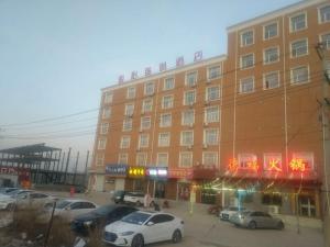 een groot gebouw met auto's geparkeerd op een parkeerplaats bij JUN Hotels Hebei Shijiazhuang Lingshou Zhongtian Commercial Building in Shijiazhuang