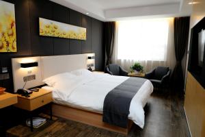 a hotel room with a large bed and two chairs at Thank Inn Chain Hotel Shandong Linyi Junan County Longshan Road in Linyi