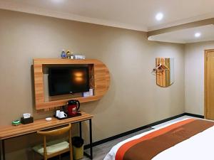 1 dormitorio con 1 cama y escritorio con TV en JUN Hotels Chongqing Yubei District Jiangbei International Airport Airport Plaza en Yubei