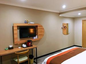 a bedroom with a bed and a desk with a tv at JUN Hotels Chongqing Yubei District Jiangbei International Airport Airport Plaza in Yubei
