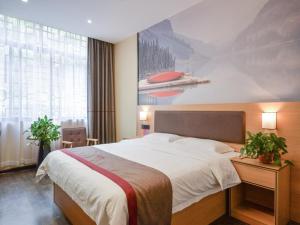 a bedroom with a large bed and a painting on the wall at Thank Inn Chain Hotel Hunan Hengyang Nanyue District Hengshan Road Nanyue Temple in Hengyang