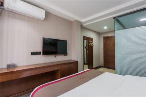 um quarto com uma cama e uma televisão na parede em Thank Inn Chain Hotel Shanxi Taiyuan Wanbolin District Wanxiang City em Taiyuan