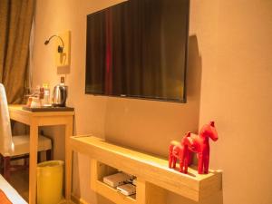 two red horses sitting on a shelf under a television at JUN Hotels Yunnan Kunming Wuhua District Changyuan Middle Road in Kunming