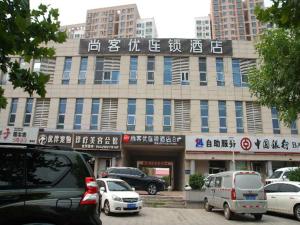 Thank Inn Chain Hotel Tianjing Jingnan District Balitai Town Industrial Park في تيانجين: مبنى كبير فيه سيارات تقف امامه