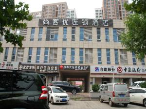 ein großes Gebäude mit davor geparkt in der Unterkunft Thank Inn Chain Hotel Tianjing Jingnan District Balitai Town Industrial Park in Tianjin