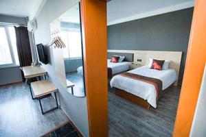 a hotel room with two beds and a mirror at JUN Hotels Shandong Weihai Huancui District High Speed Rail North Station Store in Weihai