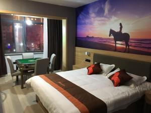 una habitación de hotel con una cama y una foto de una persona montando un caballo en JUN Hotels Anhui Fuyang Yingshang County Guanzhong Avenue Store, en Fuyang