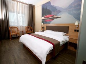 a large bed in a hotel room with a painting on the wall at Thank Inn Chain Hotel Shandong Dezhou Lingcheng District Lingzhou Road Ginza in Dezhou