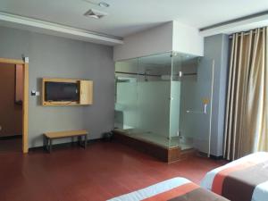 um quarto com uma cabina de duche em vidro e uma televisão na parede em JUN Hotels Jiangxi Nanchang Xiyuan em Nanchang