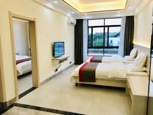 a hotel room with two beds and a television at Thank Inn Chain Hotel Hainan Oriental City Triangle Park in Dongfang