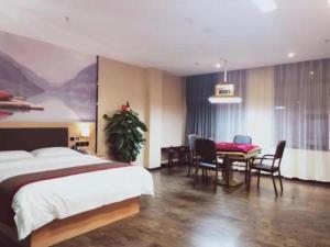 a bedroom with a bed and a table and chairs at Thank Inn Chain Hotel Jiangmen Kaiping Shuikou Passenger Transport Station in Jiangmen