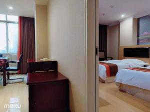 a hotel room with two beds and a desk and a table at JUN Hotels Hunan Zhuzhou Lusong District Central Plaza in Zhuzhou