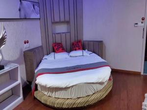 ein Schlafzimmer mit einem großen Bett mit roten Kissen darauf in der Unterkunft JUN Hotels Shanghai Chongming Xuegong Road Meizhou Road in Shanghai