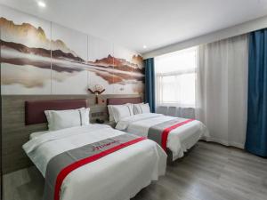 a hotel room with two beds and a painting on the wall at JUN Hotels Shanxi Taiyuan Yingze District Chaoyang Street Store in Taiyuan