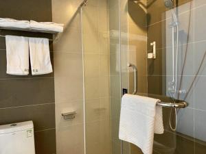 een badkamer met een douche en een glazen deur bij Up And In Qingdao Jimo District Aoshanwei Blue Silicon Valley in Qingdao