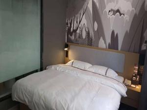 a bedroom with a white bed with a painting on the wall at Thank Inn Chain Hotel Anhui Suzhou Lingbi County People's Hospital Zhongxiu Jincheng in Suzhou