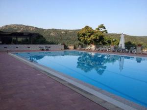 a large blue swimming pool with tables and chairs at Hotel Ristorante Gusana in Gavoi