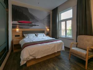 een slaapkamer met een bed, een stoel en een raam bij Thank Inn Chain Hotel Jiangsu Suzhou Changshu Haiyu Town in Changshu