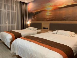 two beds in a hotel room with a painting on the wall at JUN Hotels Hebei Baoding Rongcheng Banzheng North Street Store in Baoding