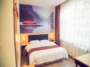 a bedroom with a large bed with a painting on the wall at Thank Inn Chain Hotel Sanmenxia Wanda Plaza New Gantang Road in Sanmenxia