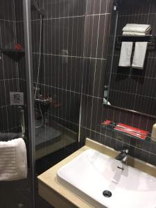 a black tiled bathroom with a sink and a shower at Thank Inn Chain Hotel Changzhi Qingyang Manor in Changzhi
