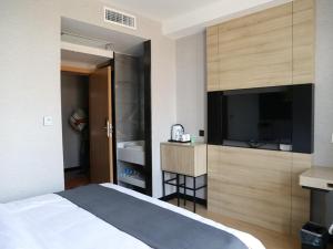 a hotel room with a bed and a flat screen tv at Thank Inn Chain Hotel Shanxi Jinzhong Yuci District Yunhua Street in Jinzhong