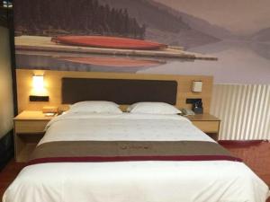 a large bed in a hotel room with a large bedspread at Thank Inn Chain Hotel Guangdong Heyuan Yuancheng District Heyuan Avenue North White Bailingtou Gaotang Store in Heyuan