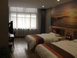 una habitación de hotel con 2 camas y un cuadro en la pared en JUN Hotels Hebei Baoding Rongcheng Baiyangdian High-Speed Railway Station, en Baoding