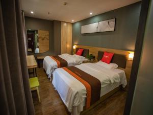 a hotel room with two beds with red pillows at JUN Hotels Jiangsu Nanjing Hongyuan Avenue Subway Station in Nanjing