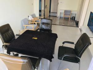 um quarto com cadeiras e uma mesa com um cobertor preto em Thank Inn Chain Hotel Hainan Oriental City Triangle Park em Dongfang