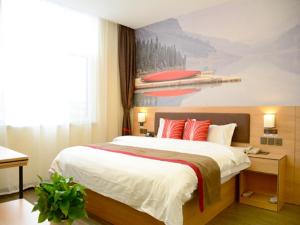 a bedroom with a large bed with a painting on the wall at Thank Inn Chain Hotel Shanxi Taiyuan Xiaodian District Zhenwu Road in Taiyuan