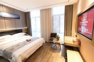 um quarto de hotel com uma cama grande e uma televisão de ecrã plano em Thank Inn Chain Hotel Ganzhou Zhanggong District Wanxiang City em Ganzhou