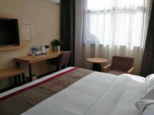 a hotel room with a bed and a desk and a television at Thank Inn Chain Hotel Anhui Suzhou Lingbi County Qimeishan Road Store in Suzhou