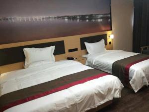 a hotel room with two beds and a painting on the wall at Thank Inn Chain Hotel Anhui Bozhou Qiaocheng District Jian'an Road Wanfu Store in Bozhou