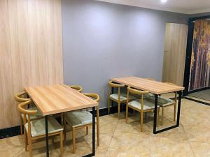 2 Holztische und -stühle in einem Raum mit einer Wand in der Unterkunft JUN Hotels Chongqing Yubei District Jiangbei International Airport Airport Plaza in Yubei
