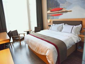 una habitación de hotel con una cama grande, mesas y sillas en Thank Inn Chain Hotel Huaihua Tongdao Bus Station, en Tongdao