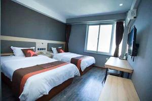 a hotel room with two beds and a television at JUN Hotels Shandong Weihai Huancui District High Speed Rail North Station Store in Weihai