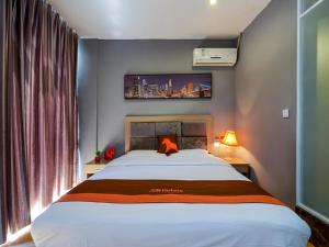 a bedroom with a large white bed and a window at JUN Hotels Chongqing Nan'an Nanping Dongmo in Chongqing