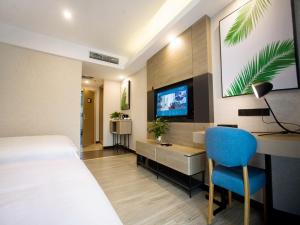 um quarto de hotel com uma cama, uma secretária e uma televisão em Up And In Baotou Qingshan District Central International em Baotou