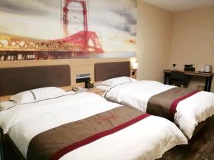 two beds in a hotel room with a painting on the wall at Thank Inn Chain Hotel Hebei Baoding Wangdu County Bus Station in Baoding