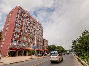 a large red building on a city street with cars at JUN Hotels Hunan Changsha Huannghua Airport in Changsha