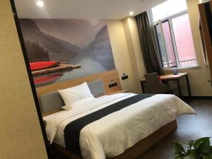 een slaapkamer met een groot bed en een schilderij aan de muur bij Thank Inn Chain Hotel Liaocheng Yanggu County Fucheng in Liaocheng