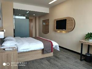 a bedroom with a bed and a tv on the wall at Thank Inn Chain Hotel Shandong Qingdao Huangdao West Coast Bus Station in Qingdao