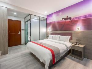 a bedroom with a large bed with a painting on the wall at JUN Hotels Shanxi Taiyuan Yingze District Chaoyang Street Store in Taiyuan