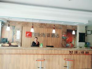 une femme assise au bar d'un restaurant dans l'établissement JUN Hotels Lu'an Huoshan County Huayuan Road, à Lu'an